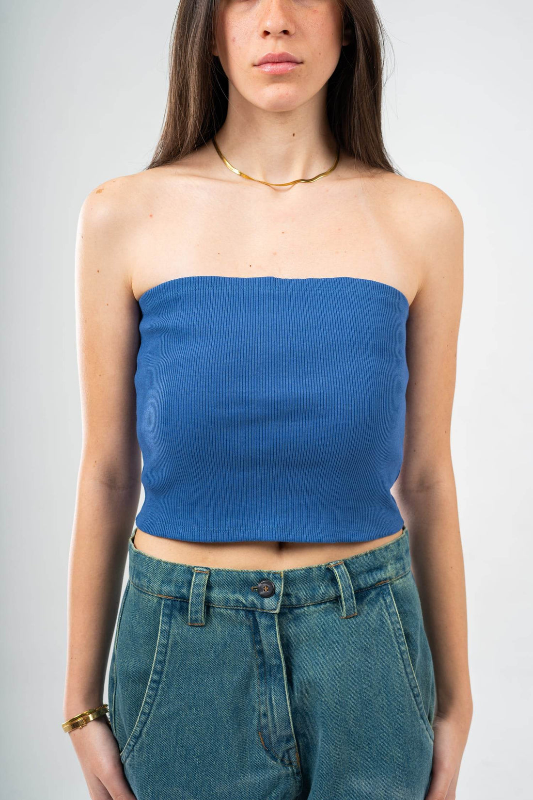 Woman wearing a black comfy strapless tube top with casual gray pants and accessories