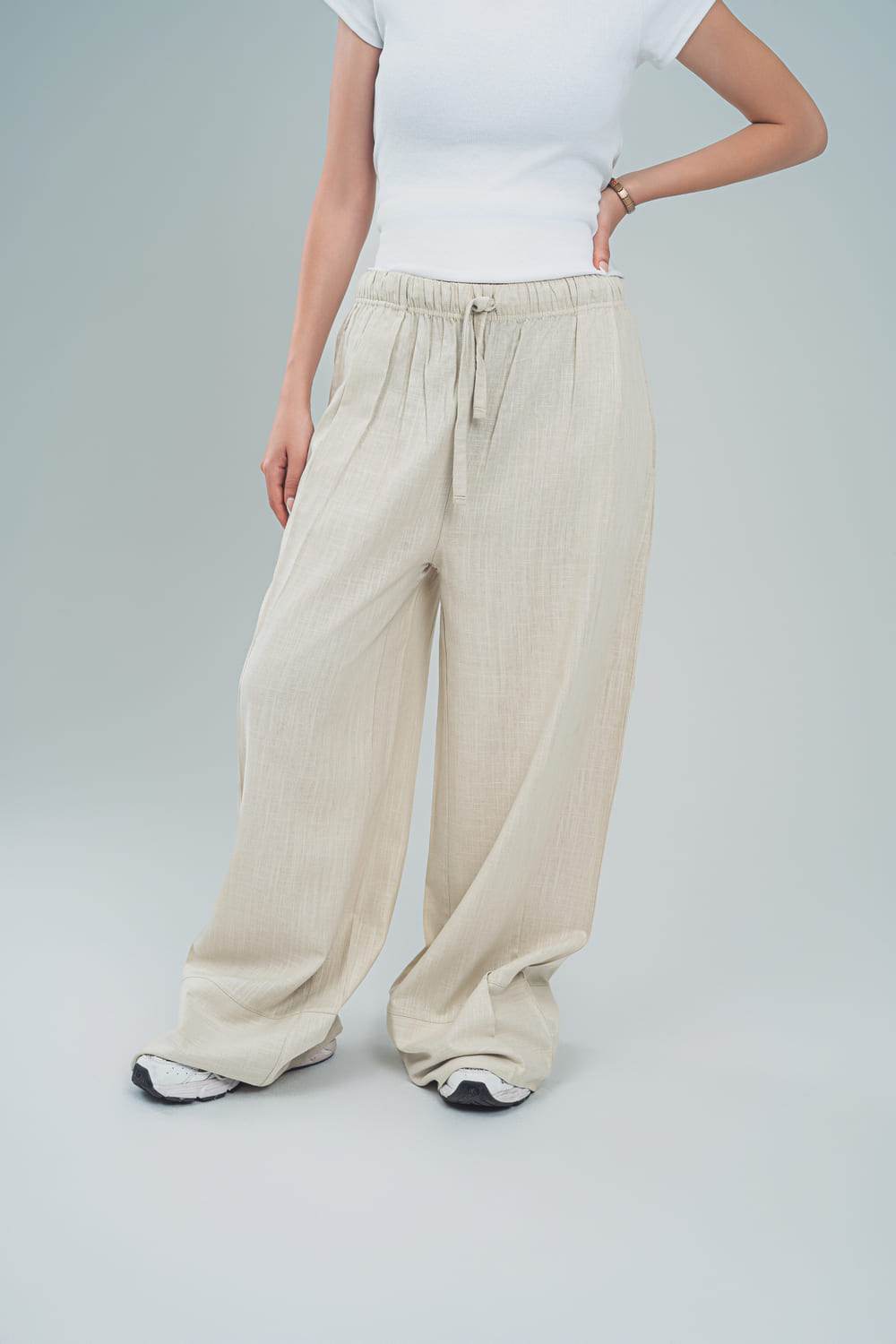 Beige linen palazzo trousers for women with drawstring waist by FAIR & SQUARE paired with white top and sneakers