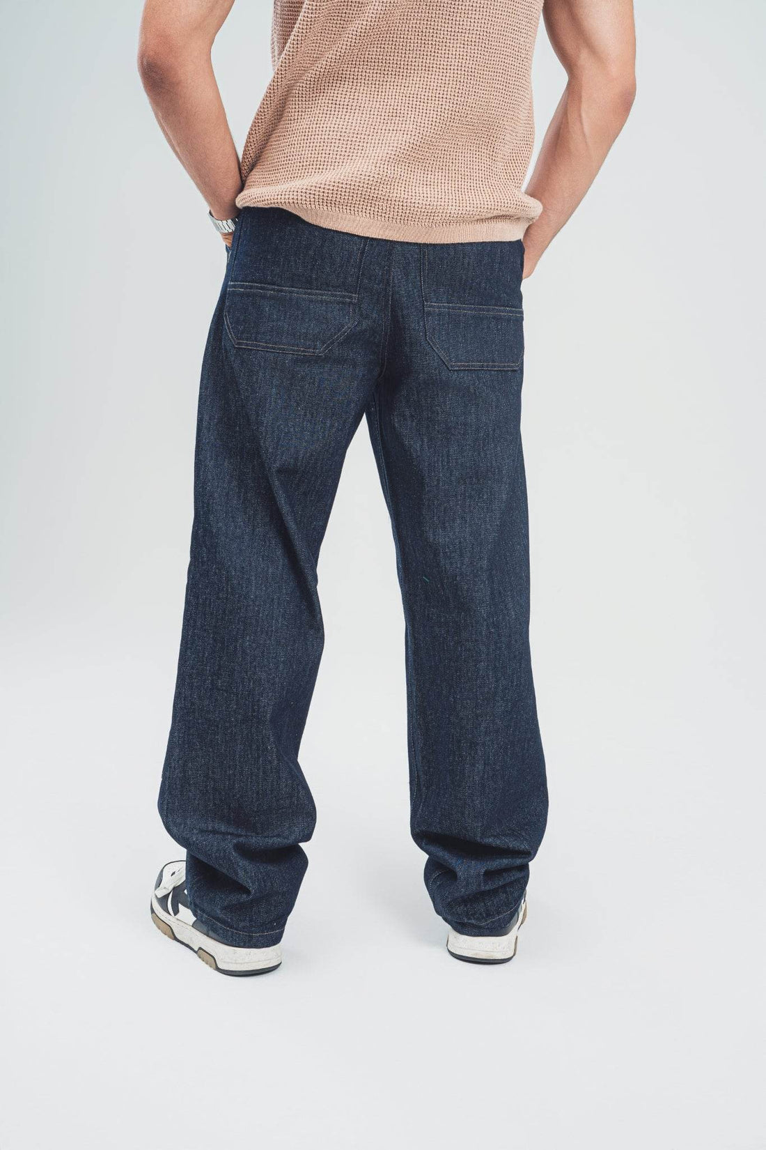 Man wearing loose fit raw denim jeans for men by FAIR & SQUARE with casual sneakers and beige shirt