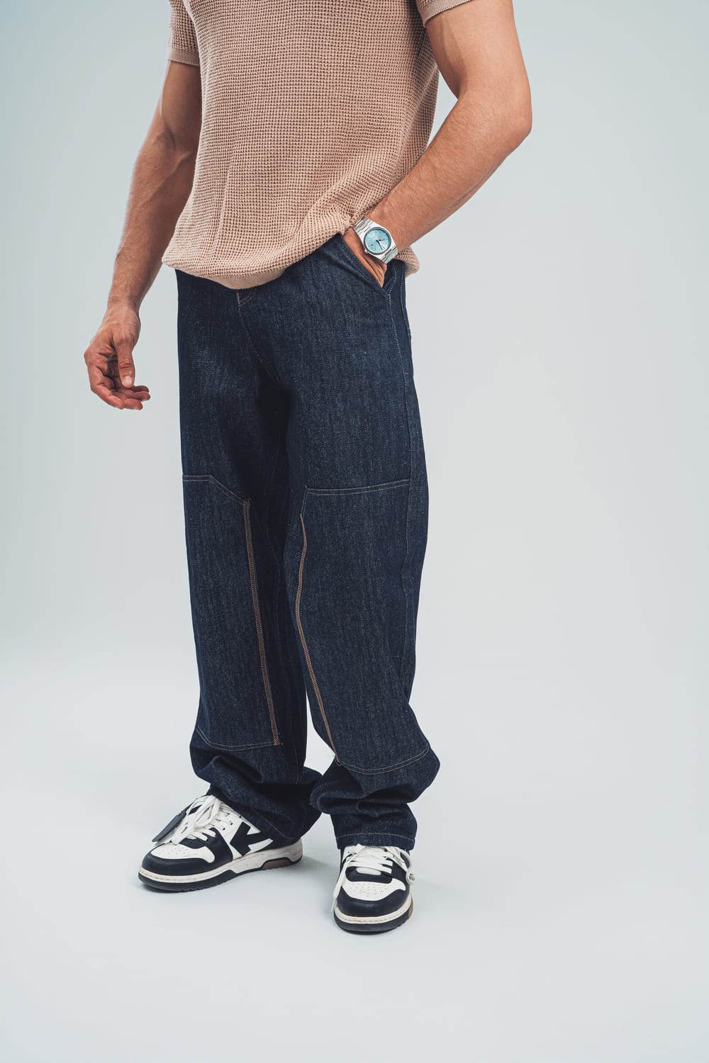 Man wearing loose fit raw denim jeans for men by FAIR & SQUARE with casual sneakers and beige shirt