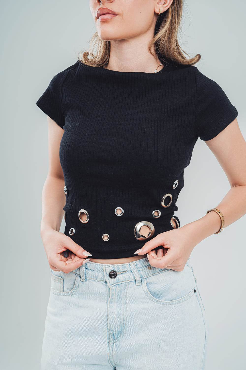 FAIR & SQUARE black studded crop top for women with circular metal accents worn with light blue jeans