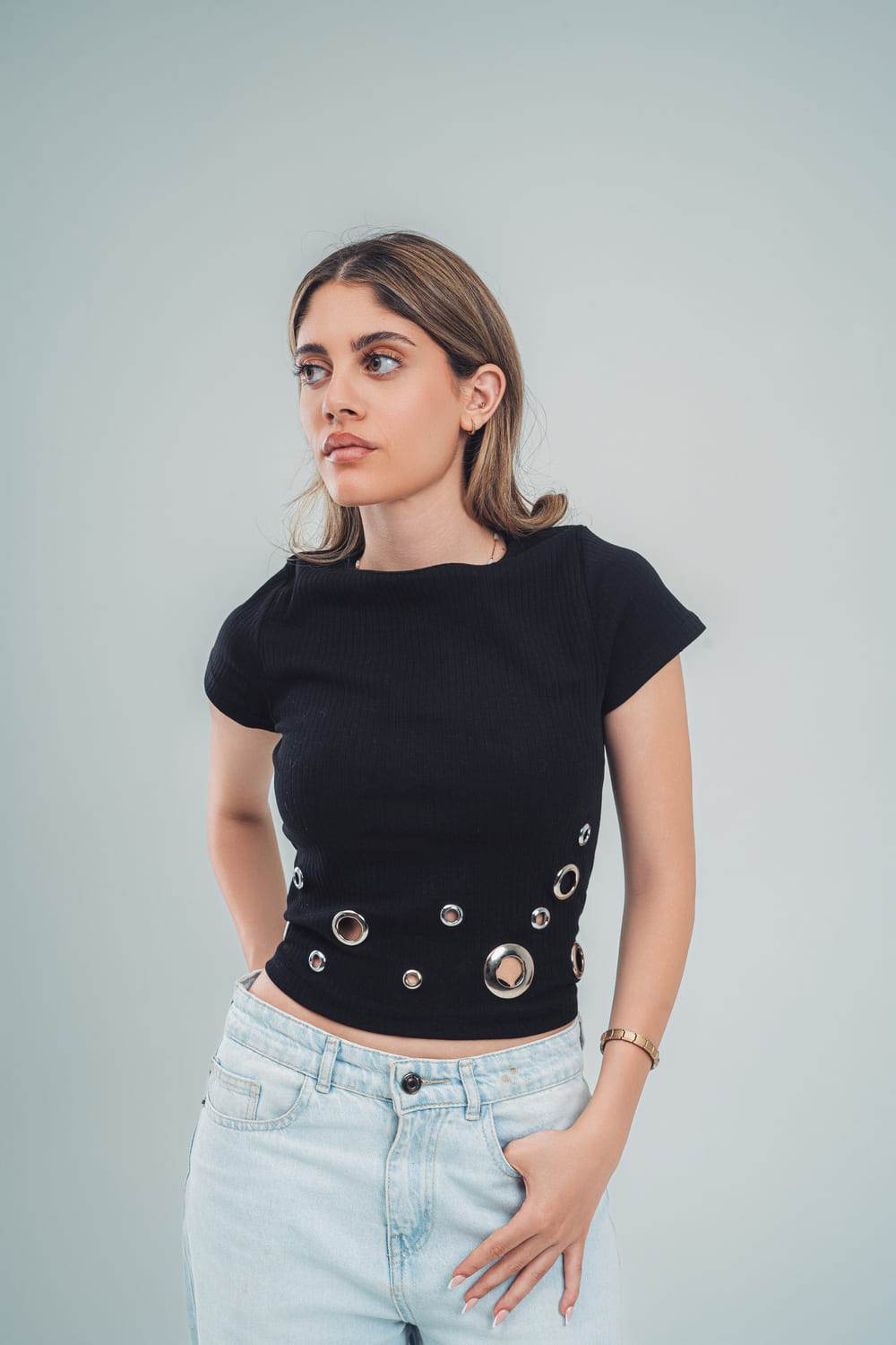 FAIR & SQUARE black studded crop top for women with circular metal accents worn with light blue jeans